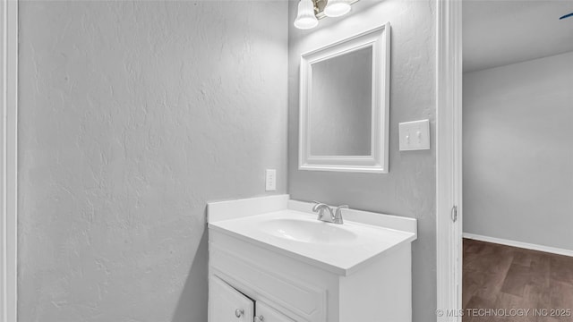 bathroom with a textured wall, wood finished floors, and vanity