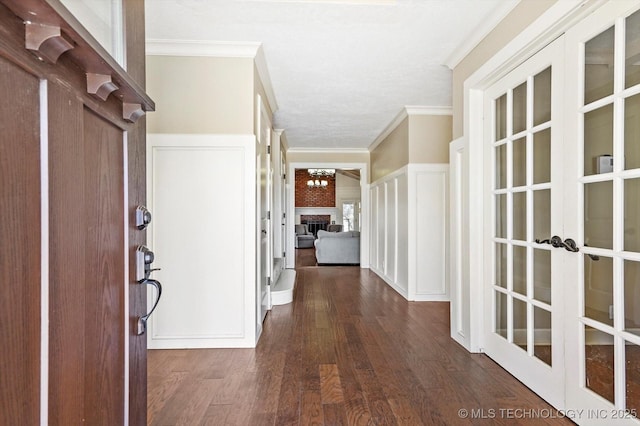 corridor with ornamental molding, a decorative wall, dark wood-style flooring, and french doors