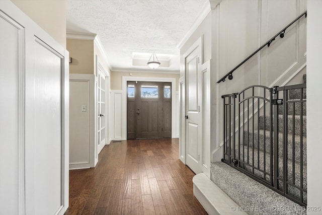 entrance foyer featuring crown molding, stairway, dark wood-type flooring, and a textured ceiling