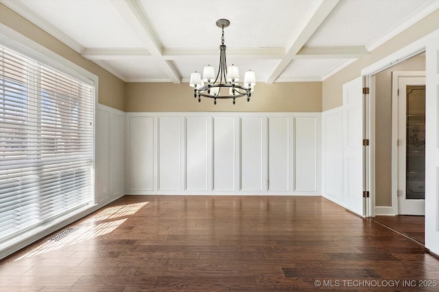 unfurnished dining area with coffered ceiling, beam ceiling, a decorative wall, and wood finished floors