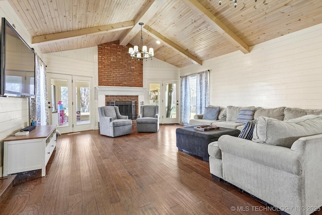 living area featuring dark wood-style floors, wood ceiling, an inviting chandelier, a brick fireplace, and beam ceiling