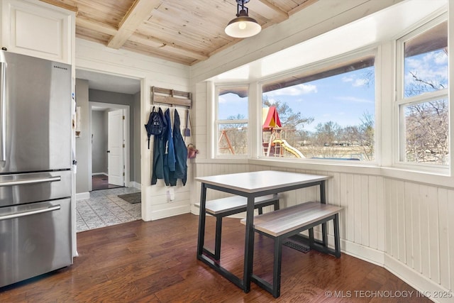 dining area featuring wooden ceiling, wood walls, baseboards, beamed ceiling, and dark wood finished floors