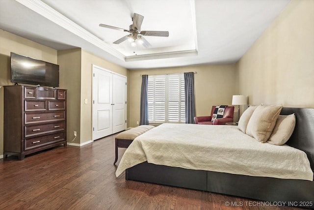 bedroom featuring a ceiling fan, baseboards, a closet, dark wood-style floors, and a raised ceiling