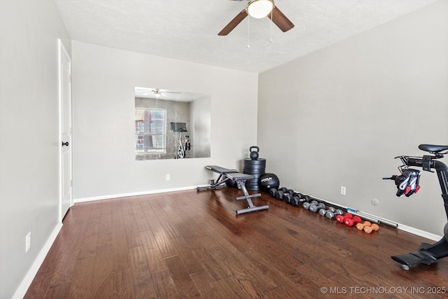 exercise room featuring a ceiling fan, a textured ceiling, baseboards, and wood finished floors