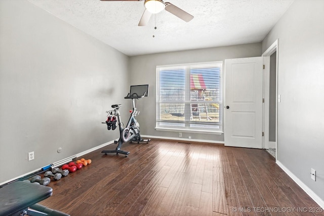 workout area featuring a textured ceiling, baseboards, and wood finished floors