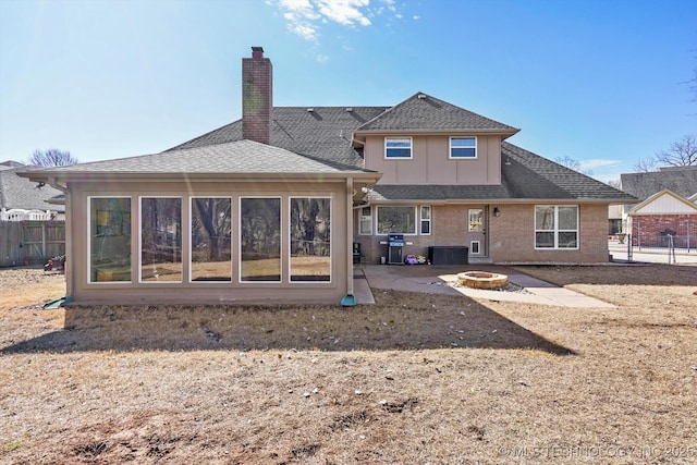 rear view of house with a patio, an outdoor fire pit, fence, roof with shingles, and a chimney