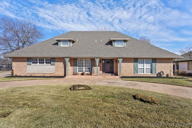 view of front of house with a shingled roof, curved driveway, a front lawn, and brick siding