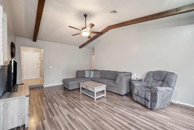 living room featuring baseboards, visible vents, a ceiling fan, wood finished floors, and vaulted ceiling with beams