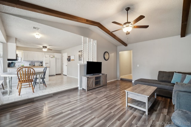 living room with lofted ceiling, a textured ceiling, visible vents, and a ceiling fan