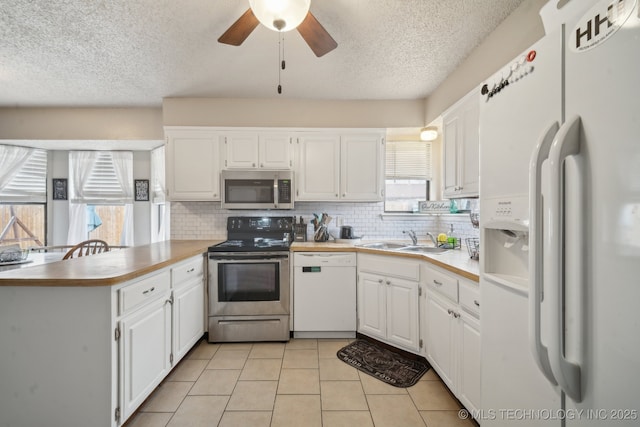 kitchen with a peninsula, white cabinets, stainless steel appliances, and a sink