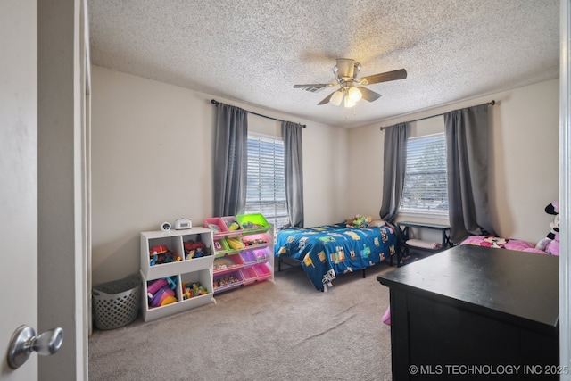 bedroom with a textured ceiling, carpet floors, multiple windows, and a ceiling fan