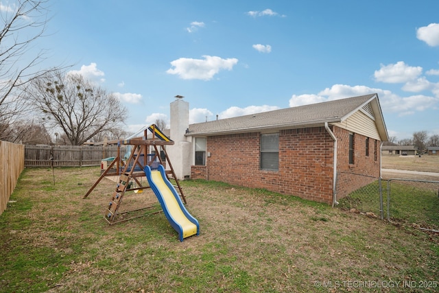 exterior space featuring a yard, a playground, brick siding, and a chimney