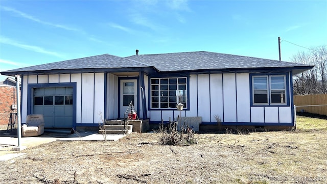 view of front of property featuring an attached garage, a shingled roof, fence, and board and batten siding