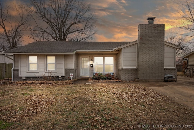 view of front of home with a chimney, fence, and brick siding