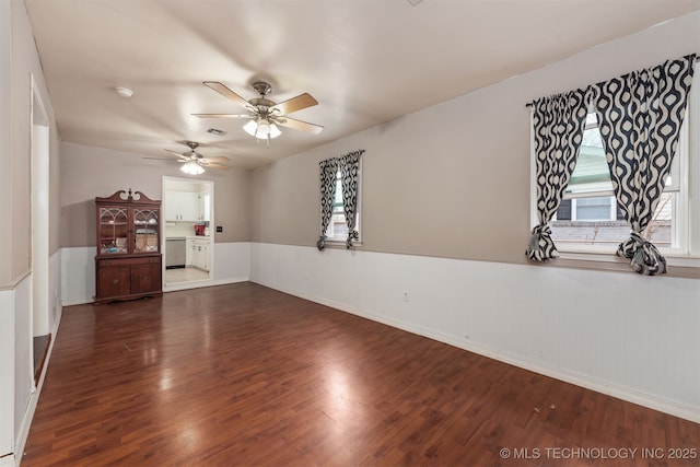 unfurnished room featuring ceiling fan, visible vents, wood finished floors, and wainscoting