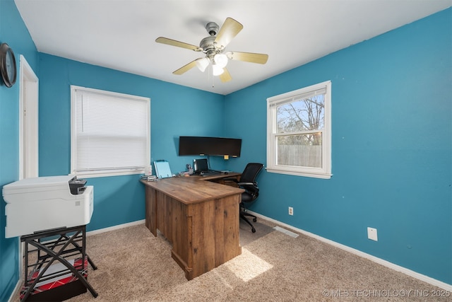 carpeted office space featuring baseboards and a ceiling fan