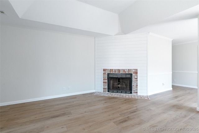 unfurnished living room featuring a fireplace with flush hearth, baseboards, and wood finished floors