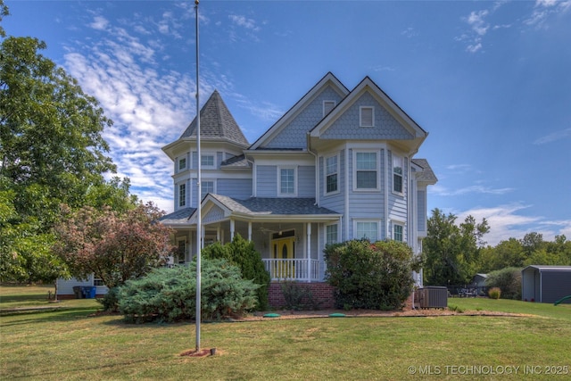 victorian-style house featuring an outbuilding, a porch, a front lawn, and central air condition unit