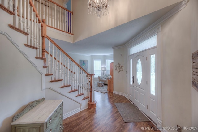 entryway featuring a high ceiling, stairs, ornamental molding, and wood finished floors