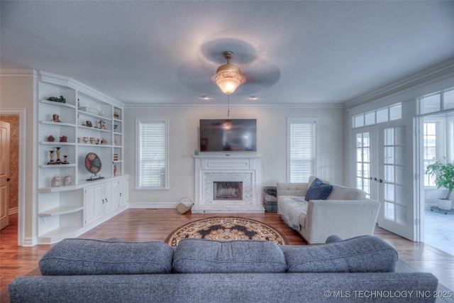 living room with ornamental molding, wood finished floors, french doors, and a high end fireplace