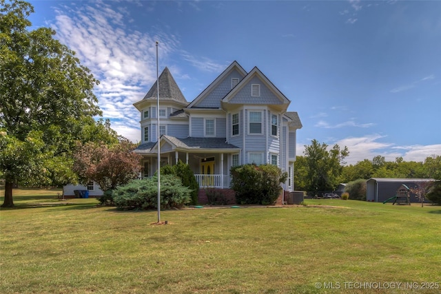 victorian home with covered porch, a front lawn, and central air condition unit