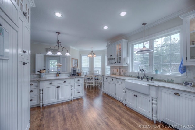 kitchen with crown molding, white cabinets, a sink, and tasteful backsplash