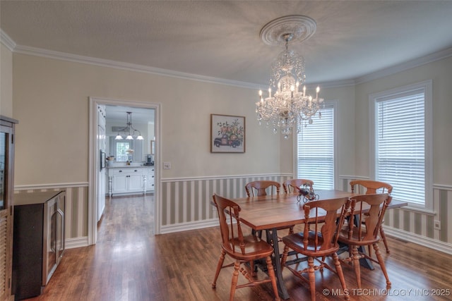 dining space with an inviting chandelier, baseboards, ornamental molding, and wood finished floors