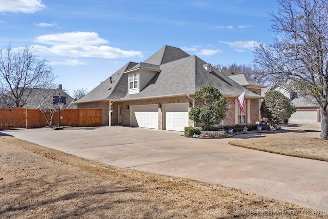 view of home's exterior featuring a shingled roof, concrete driveway, an attached garage, fence, and brick siding