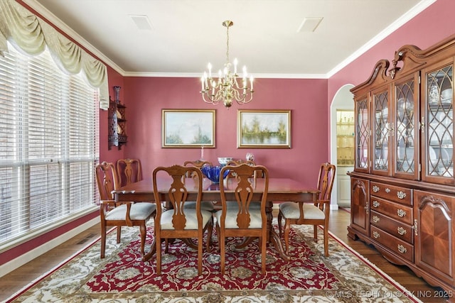 dining space with a chandelier, arched walkways, crown molding, and wood finished floors