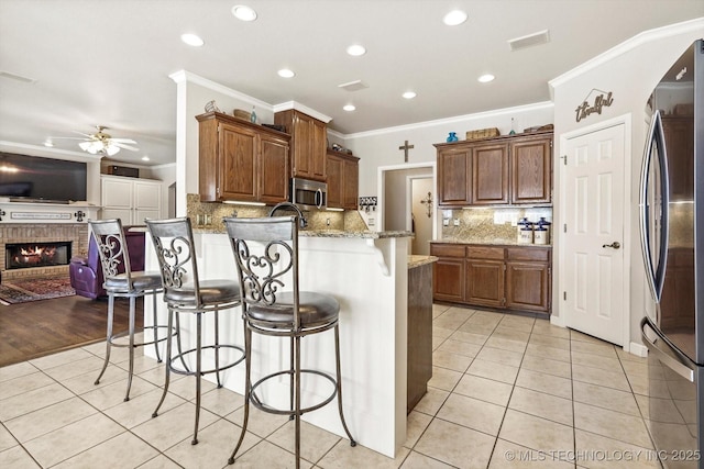 kitchen with light tile patterned floors, a breakfast bar area, visible vents, open floor plan, and appliances with stainless steel finishes