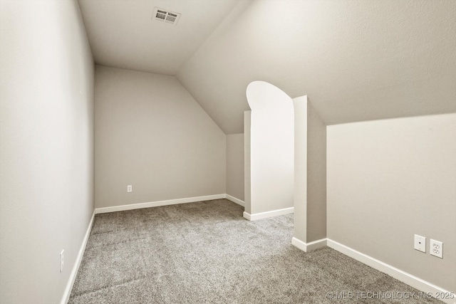 additional living space with vaulted ceiling, carpet flooring, visible vents, and baseboards