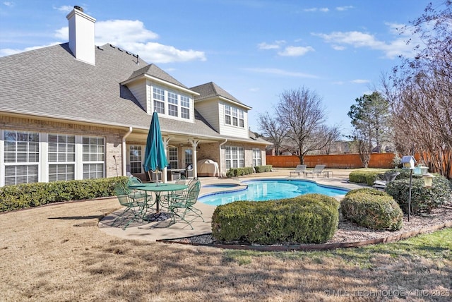 back of house featuring a fenced backyard, brick siding, a shingled roof, a chimney, and a patio area