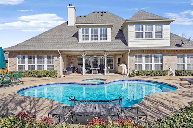 rear view of house with a patio, brick siding, an outdoor pool, and an in ground hot tub