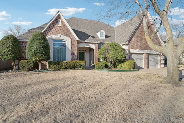 view of front facade with driveway, an attached garage, roof with shingles, and brick siding