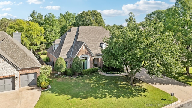 view of front of home featuring an attached garage, a front yard, concrete driveway, and brick siding