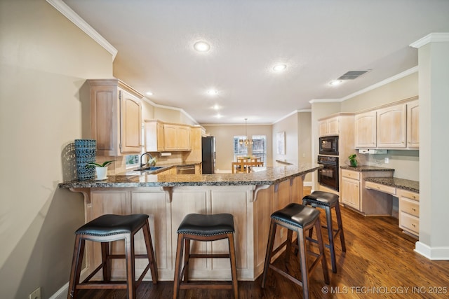 kitchen featuring a peninsula, a sink, visible vents, built in study area, and black appliances