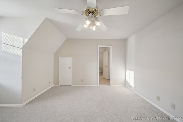 additional living space featuring light carpet, baseboards, vaulted ceiling, and a ceiling fan