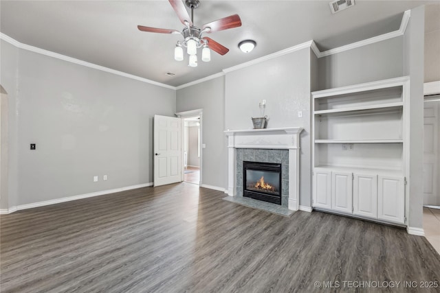 unfurnished living room with visible vents, ornamental molding, wood finished floors, a tile fireplace, and baseboards