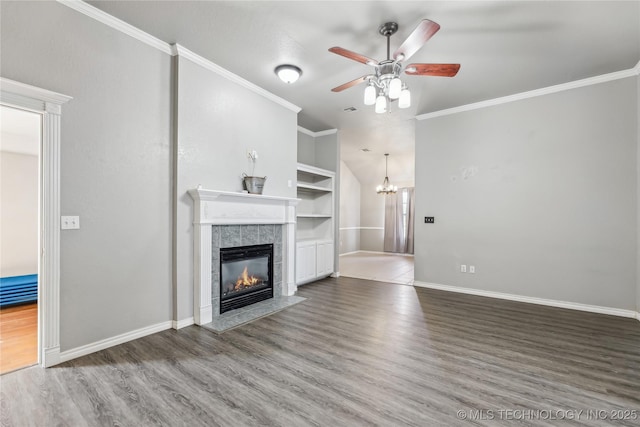 unfurnished living room featuring ornamental molding, a tiled fireplace, wood finished floors, and built in features