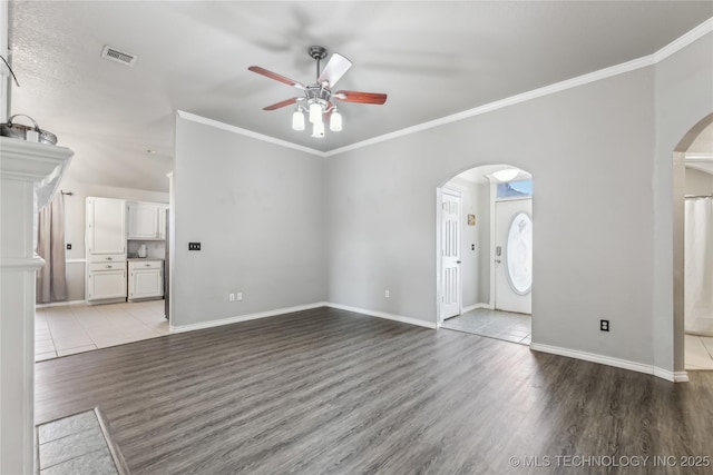 unfurnished living room featuring arched walkways, wood finished floors, visible vents, and crown molding