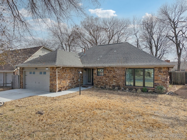 view of front of home with a garage, a shingled roof, fence, stone siding, and concrete driveway