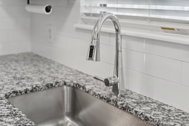 interior details featuring light stone countertops, white cabinets, and a sink