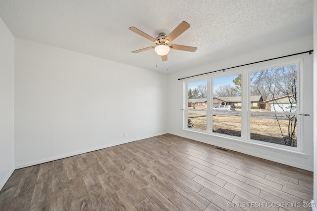 unfurnished room with visible vents, baseboards, ceiling fan, wood finished floors, and a textured ceiling