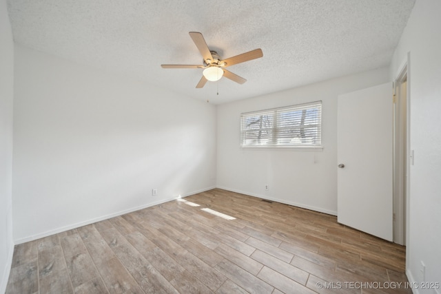 spare room featuring a textured ceiling, wood finished floors, a ceiling fan, and baseboards