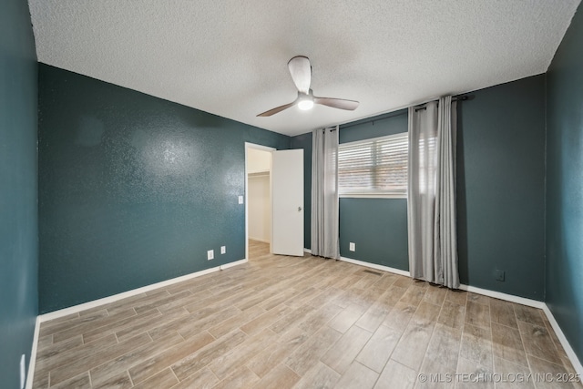 spare room with baseboards, visible vents, ceiling fan, wood finished floors, and a textured ceiling