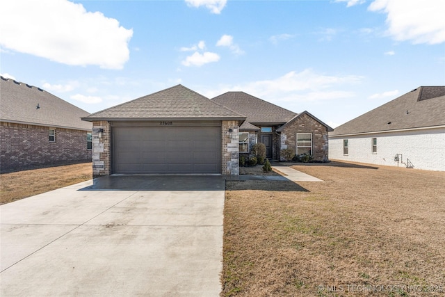 view of front of house featuring concrete driveway, roof with shingles, an attached garage, a front yard, and brick siding