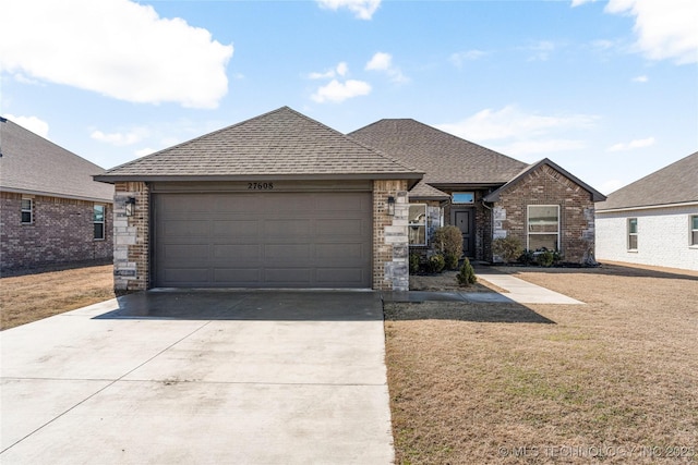 view of front of house with a garage, a front lawn, concrete driveway, and roof with shingles