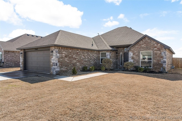 view of front facade with an attached garage, a shingled roof, a front lawn, and brick siding