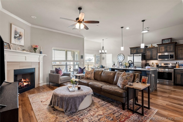 living room featuring visible vents, ornamental molding, wood finished floors, and a tile fireplace