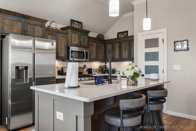 kitchen featuring dark brown cabinetry, decorative backsplash, light wood-style flooring, appliances with stainless steel finishes, and vaulted ceiling